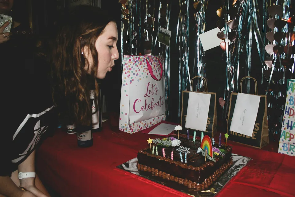 Guest blowing out candles on a birthday cake with rainbow decorations